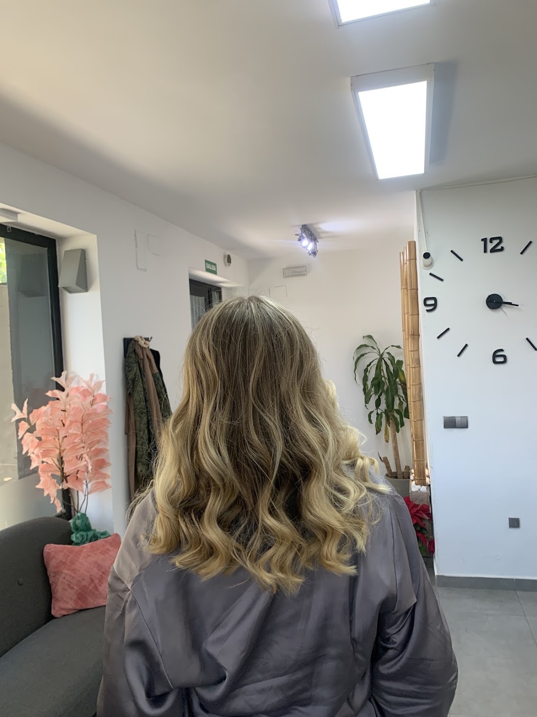 Melena media con balayage rubio y ondas, vista de espaldas dentro del salón