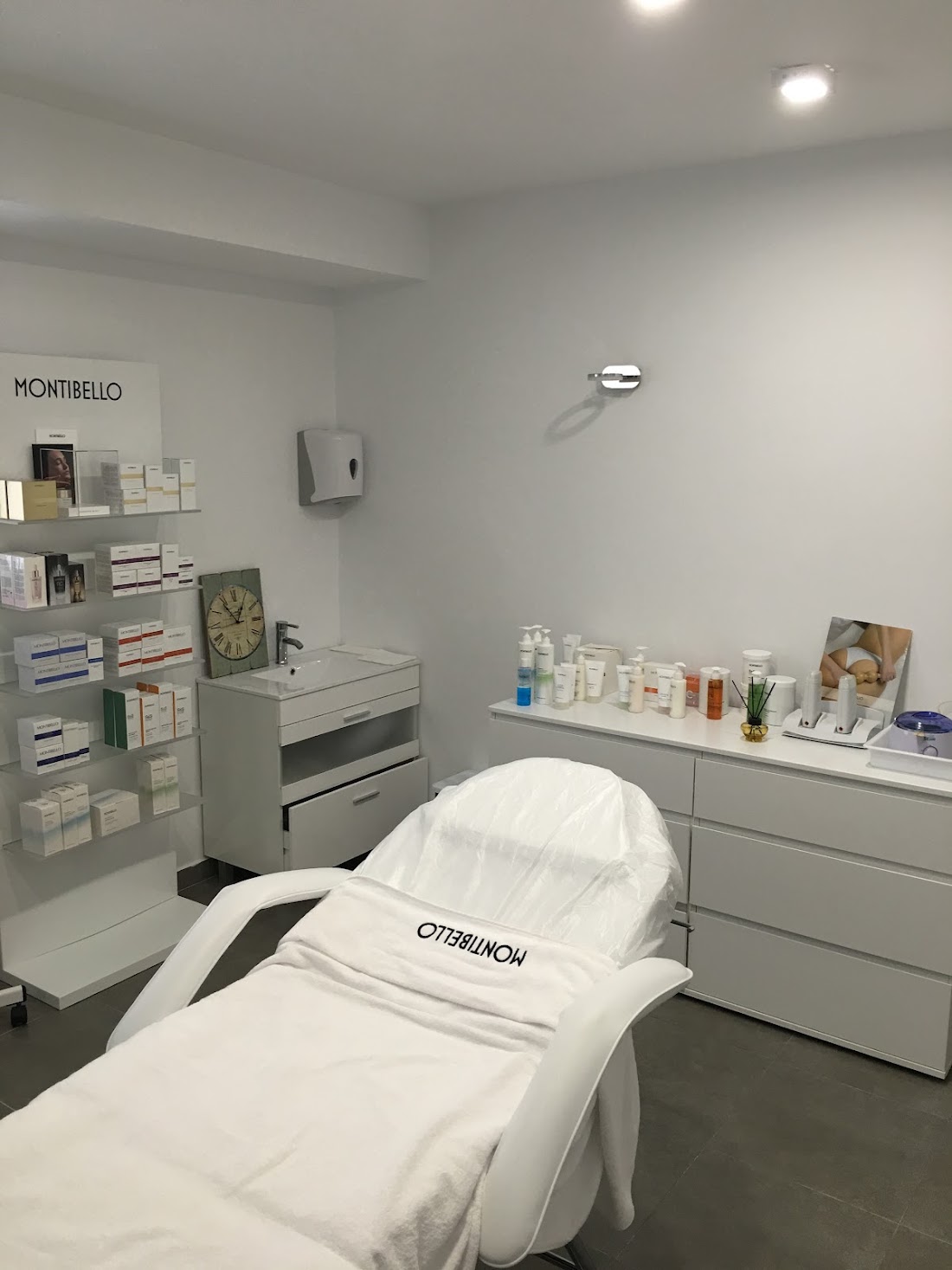 Cabina de estética con camilla blanca y productos en estanterías
