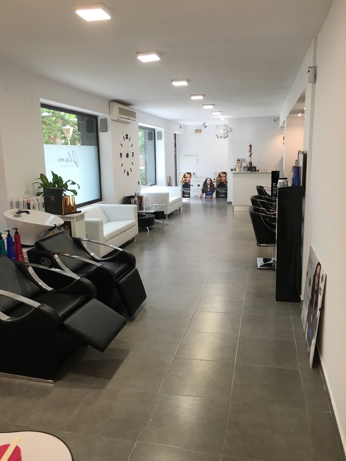 Interior del salón: lavacabezas negros, sofás blancos y tocadores al fondo